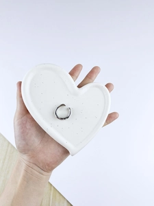 Silver irregular lava style ring displayed on a white heart ceramic jewelry tray