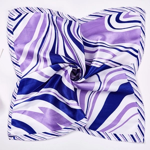 Detail of square silk scarf with wavy blue and purple patterns in a swirl display