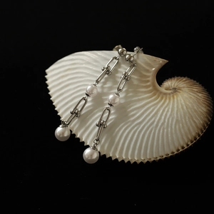 Détails de boucles d'oreilles U-link argentées avec perles sur un coquillage