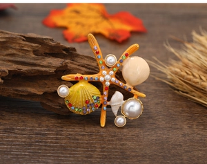 Close-up of enamel starfish brooch with pearls and rhinestones on a wooden background