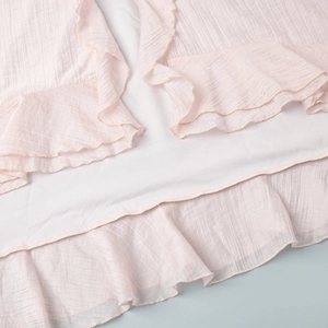 Detail of light pink crinkled fabric with ruffled hem and neat white lining stitches