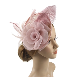 Pink fascinator hat with mesh veil and feathers shown on a model for wedding party