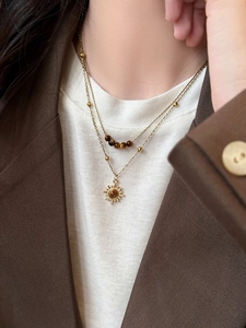 Macro detail of a golden double-layer sunflower necklace featuring brown tiger eye beads