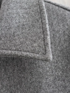 Dettaglio del risvolto di un cappotto grigio in lana con cuciture e trama del tessuto