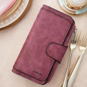 Detail of burgundy vintage long wallet with matte texture and zipper pocket on beige fabric