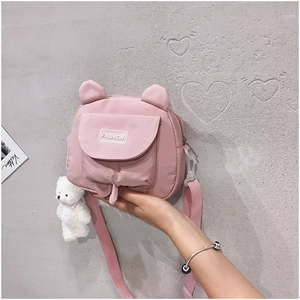 Detailed close-up of a pink nylon crossbody bag featuring cute ears and a plush bear charm