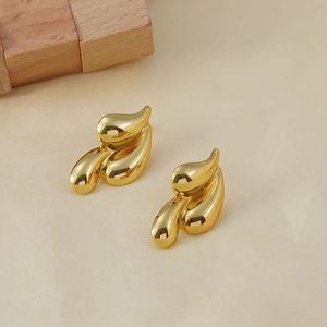 Polished 18K gold plated stainless steel fluid shape earrings on beige fabric background