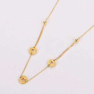Macro view of gold chain necklace featuring circular coin charms and small gold beads