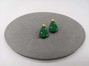 Detail von Weihnachtsbaum-Ohrsteckern mit festlichem Dekor auf grauem Samt-Display
