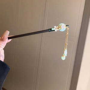Detail of wooden hair stick with white cherry blossom and green jade pendant tassel