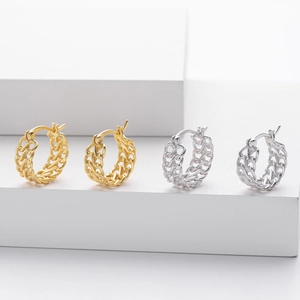 Macro shot of minimalist gold and silver curb chain hoop earrings on a white platform