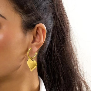 Detailed view of elegant gold heart-shaped earrings with polished finish on a model