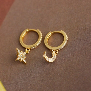 Detailed view of asymmetrical gold moon and star hoop earrings with zircon pavé setting