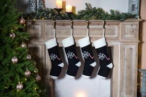 Set of four knitted Christmas stockings with snowflake and candy cane patterns on fireplace