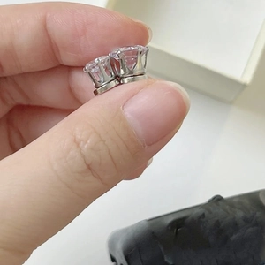 Detailed view of clear cubic zirconia magnetic studs being held by hand on silver base
