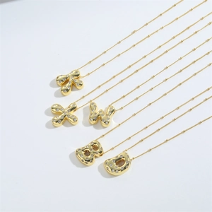 Macro detail of gold bubble letter pendants with sparkling rhinestones on fine beaded chains