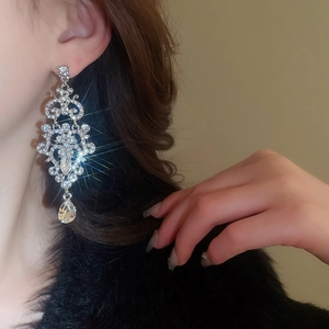 Detail of luxury teardrop chandelier earrings with sparkling crystals on model