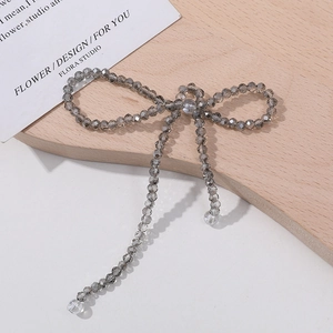 Macro shot of smoky grey crystal bow charm with delicate dangling tassels for DIY jewelry