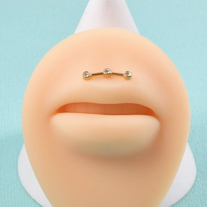 Detailed view of gold plated labret stud with three sparkling white zircons on lip model