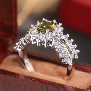 Makroaufnahme eines ovalen olivgrünen Edelsteinrings mit Zirkonia-Halo in einer Box
