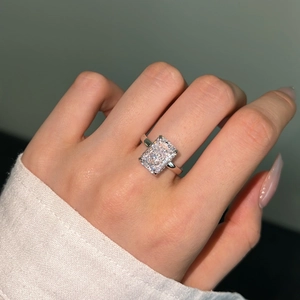 Detail of a radiant cut square stone ring on finger with polished silver band