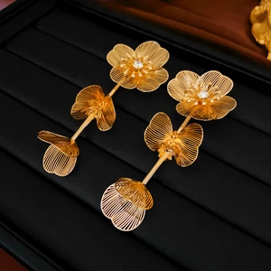 Détail macro de boucles d'oreilles fleurs dorées avec texture filaire et cristal brillant incrusté