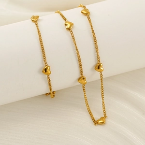 Élégant collier à breloques cœur doré exposé sur un support blanc dans un décor raffiné