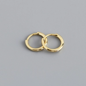 Detailed close-up of pair of polished gold sterling silver huggie hoop earrings