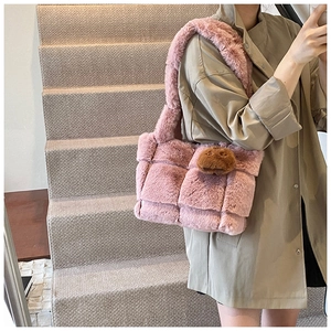 Pink plush woven shoulder bag with cute brown charm accessory on a model