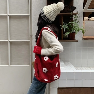 Detail of red plush tote bag with white 3D flower pattern and soft fleece texture