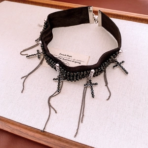 Gros plan sur un choker en velours gothique avec perles noires et pendentifs croix