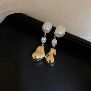 Vue détaillée de boucles d'oreilles dorées irrégulières avec perles baroques blanches