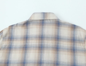 Dettaglio del colletto e delle cuciture sulla spalla di camicia beige a quadri