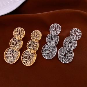 Close-up of golden and silver triple round earrings with intricate hollow mesh design