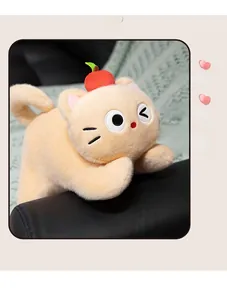 Close-up of pink cat plush with red apple hat and wink face on a cozy sofa