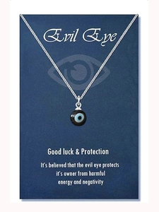 Close-up of stainless steel evil eye pendant with blue bead on a blue gift display card
