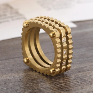 Macro detail of luxury gold gear ring with rivet studs and pave crystals in three layers