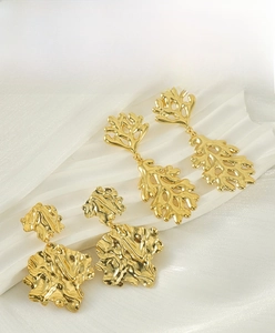 Macro detail of irregular lava leaf earrings with 18K gold plating on wavy texture