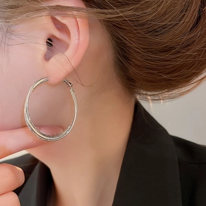 Close-up of model wearing large double-layer silver hoop earrings for a stylish look