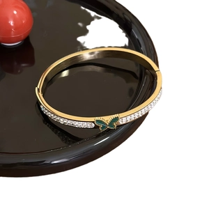 Luxury gold butterfly open bangle with sparkling cubic zirconia on a black reflective base