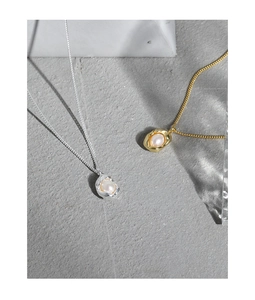 Detailed close-up of shell pearl pendants with irregular molten metal base in gold and silver