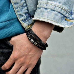 Detail of multilayer woven black leather bracelet with silver and gold metal accents