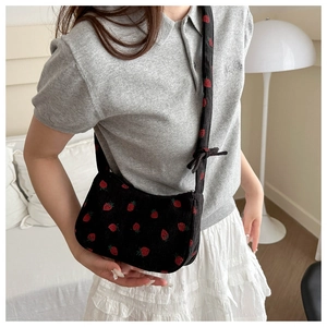 Close-up of black corduroy shoulder bag with sweet red strawberry embroidery patterns