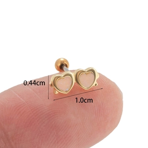 Double heart stud earrings with white opal inlay and gold base shown in hand