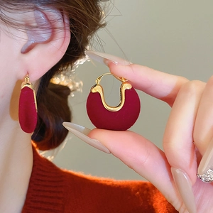 Close-up of vintage red velvet hoop earrings with gold trim worn on model's ear