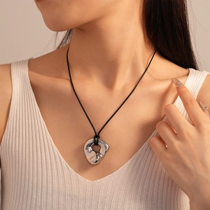 Detail of silver liquid metal heart pendant on black rope chain worn by a model