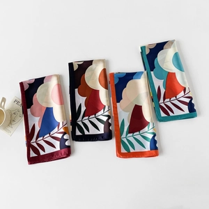Macro shot of printed silk square scarves in burgundy, black, orange, and teal colors