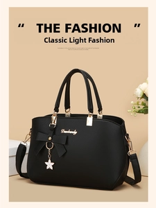 Detail of black pebbled leather tote featuring a metal floral charm and bow accent