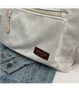 Detailed texture of beige corduroy tote bag with zipper pocket and leather fashion patch