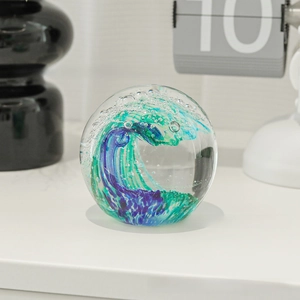 Detail of artistic glass paperweight with blue-green ocean wave and bubbles inside